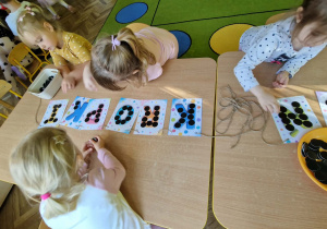 Dziewczynki układają czarne koła na literach napisu DZIEŃ KROPKI