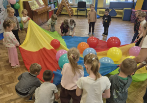 dzieci bawią się z panią chustą animacyjną i balonami