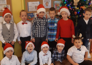 W pierwszym rzędzie siedzi: 5 chłopców mających na głowie czapki mikołajowe, w drugim rzędzie stoi: 6 chłopców, 3je z nich ma na głowie czapki mikołajowe