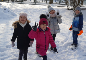 Na śniegu stoją od lewej dziewczynka, dziewczynka, dziewczynka i chłopiec