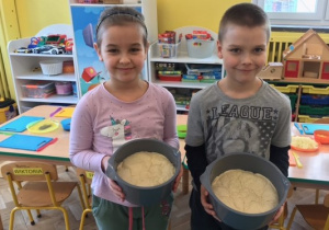 dziewczynka i chłopiec trzymają miski z ciastem na pizze