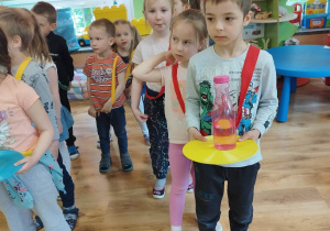 Dzieci przenoszą plastikową butelkę z wodą na plastikowym krążku