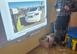 Ekspert pokazuje samochod elektryczny na stacji ładowania