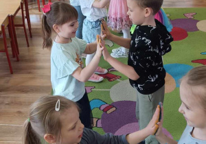 Dzieci dotykają się rękami pomalowanymi farbą łącząc kolory.