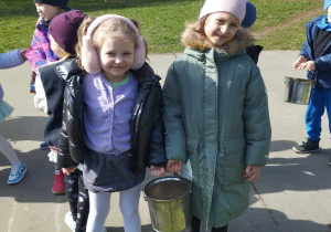 Dwie dziewczynki trzymają wiaderko z ziarnami i pozują do zdjęcia.