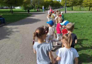 Dzieci w parach idą parkową alejką.