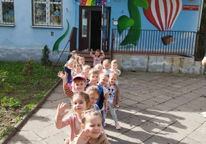 Dzieci stoją przed budynkiem przedszkola.