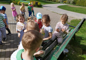 Dzieci bawią się w parku przy ławce.