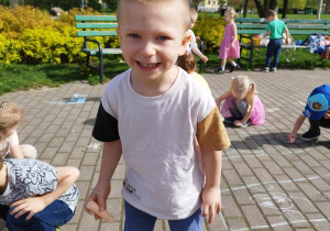 Chłopiec w parku trzyma kredę.