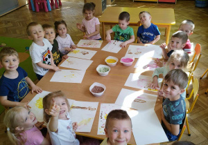 Dzieci przy stole malują jadalnymi farbami.