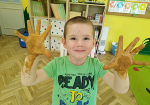 Chłopiec pokazuje dłonie w jadalnej farbie.