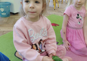 Dziewczynka trzyma liść szpinaku.