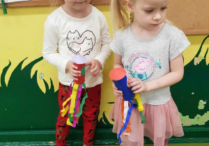 Dwie dziewczynki trzymają rakiety z papierowych rolek.