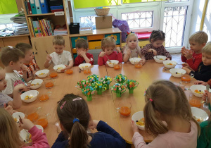 Dzieci wspólnie spożywają sałatkę przygotowaną przez dziewczynki.