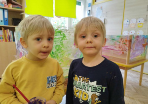 Dwóch chłopców stoi w przedszkolnej sali.