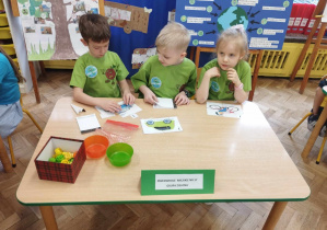 Dzieci w zielonych koszulkach układają puzzle przy stole