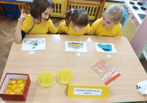 Dzieci w żółtych koszulkach układają puzzle przy stole