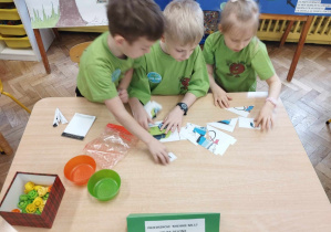 dzieci w zielonych oszulkach układają puzzle przy stole