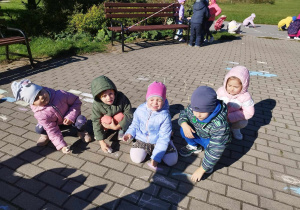 Dzieci rysują kredą na chodniku.