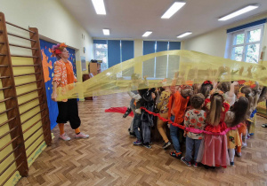 Dzieci otoczone sigumą nad którymi pani unosi żółty materiał