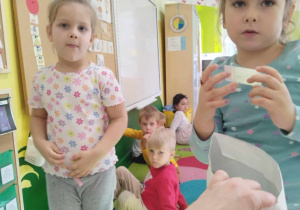 Dziewczynki uczestniczą w zajęciach edukacyjnych, w tle dzieci.