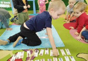 Dzieci uczestniczą w zabawie edukacyjnej „Domino Pióra”.