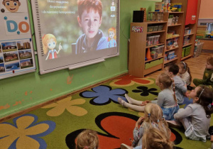 Dzieci oglądają film edukacyjny na tablicy interaktywnej.