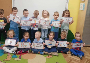 Dzieci z grupy 2 trzymają karty demonstracyjne z prawami dziecka.