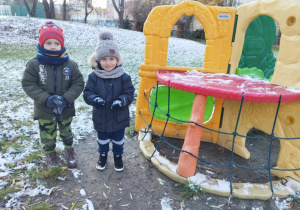 Dwóch chłopców stoi przy plastikowym sprzęcie terenowym w ogrodzie przedszkolnym.