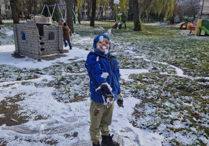 Chłopiec podrzuca do góry śnieg