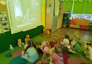 Dzieci oglądają bajkę Miś Uszatek na tablicy multimedialnej.