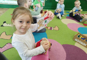 Dziewczynka trzyma kartę do zabawy matematycznej z klamerkami.