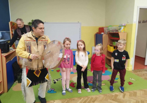 Dzieci naśladują ruchy mężczyzny w stroju mieszkańca Ameryki Północnej