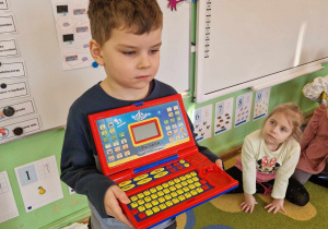 Chłopiec prezentuje dzieciom jak wygląda laptop