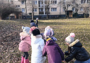 Dzieci śpiewają i tańczą w kole w ogrodzie.