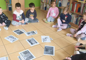 Dzieci siedzą na poduszkach i słuchają ciekawostek o kotach.