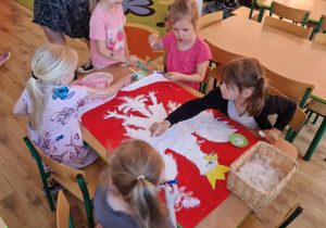 Dzieci przyklejają białe pióra na sylwete orła