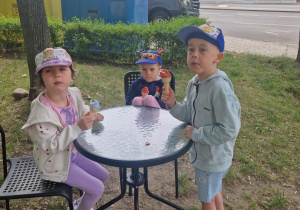 Troje dzieci siedzi przy stole i jedzą lody