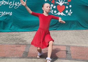 Dziewczynka w czerwonej sukience tańczy na pikniku