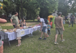 Rodzice i dzieci kosztuja słodkości na pikniku