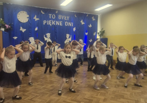 Dzieci w galowych strojach tańczą