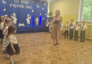 Pani mówi przez mikrofon do dzieci