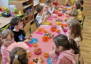 Dzieci siedzą przy stole i świętują urodziny koleżanki