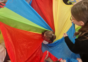 Dzieci zawijają jubilatkę w kolorową chustę