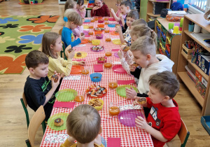 Dzieci siedzą przy stole i świętują urodziny koleżanki