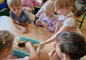 Dziewczynka częstuje ciasteczkami dzieci