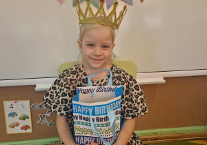 Jubilatka w koronie trzyma w ręku torbę z cukierkami