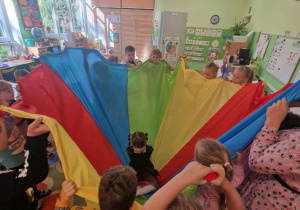 Dzieci owijają dziewczynkę w kolorową chustę