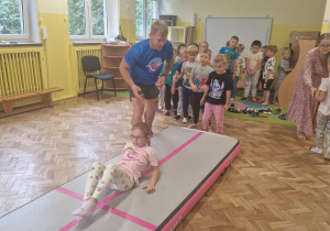 Dzieci wykonują przewroty na materacu