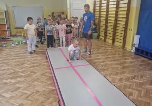 Dzieci wykonują przewroty na materacu
